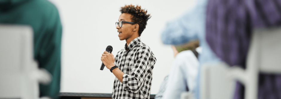 Young man standing holding a microphone making an announcement